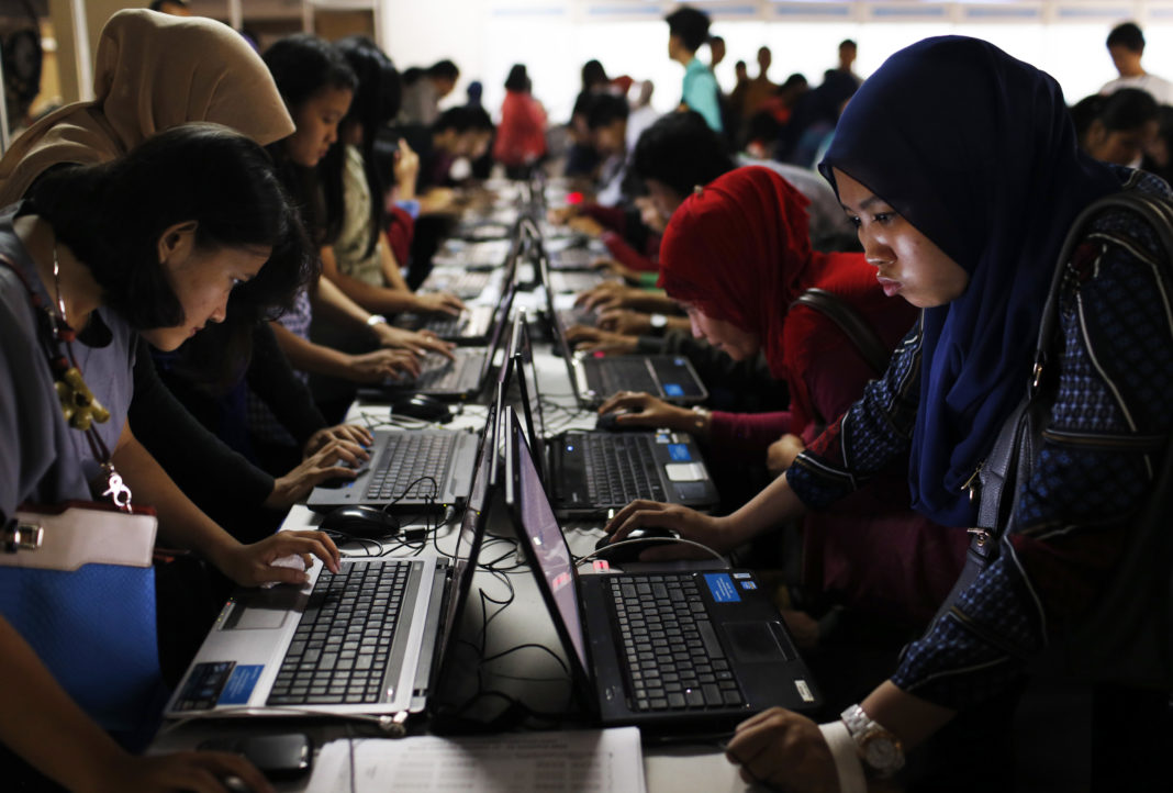 Indonesian youths fill up job application forms on laptops provided by the organizers at Kompas Karier Fair in Jakarta